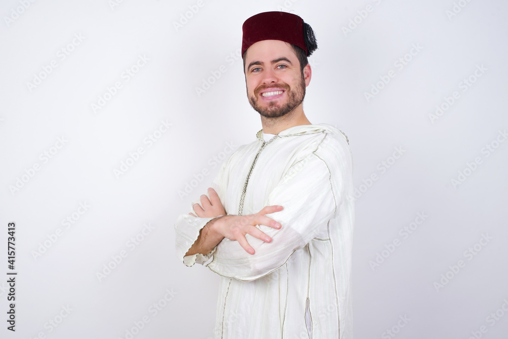 elke keer Zullen zuigen Image of cheerful young handsome Caucasian man wearing Arab djellaba and  Fez hat over white wall with arms crossed. Looking and smiling at the  camera. Confidence concept. Stock Photo | Adobe Stock