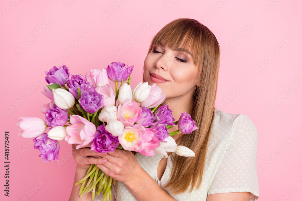 Portrait of attractive cheery dreamy girl holding in hands smelling flowers congrats romance event isolated over pink pastel color background Portrait of attractive cheery dreamy girl holding in hands smelling flowers congrats romance event isolated over pink pastel color background