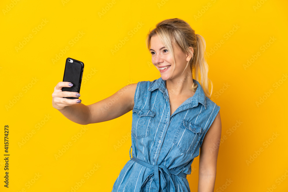 Young Russian woman isolated on yellow background making a selfie with mobile phone Young Russian woman isolated on yellow background making a selfie with mobile phone