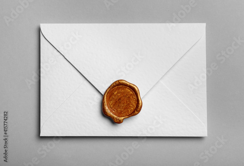 White envelope with wax seal on grey background, top view photo