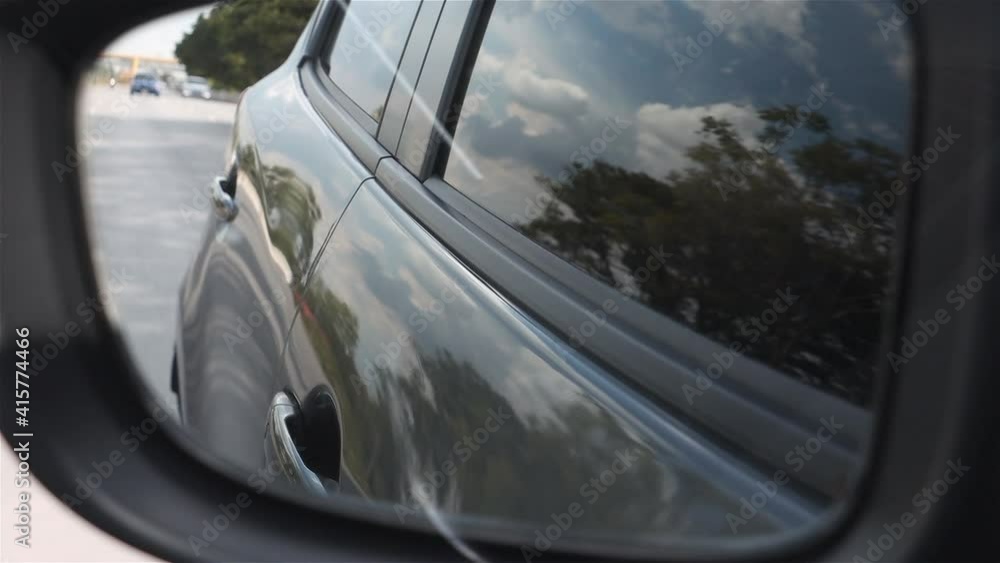 A Looking in the rearview mirror while driving on the highway. A Looking in the rearview mirror while driving on the highway.