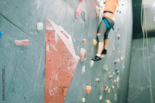 Rocks on climbing wall. Fitness, extreme sport, bouldering, people and healthy lifestyle concept - man and woman exercising at indoor climbing gym.