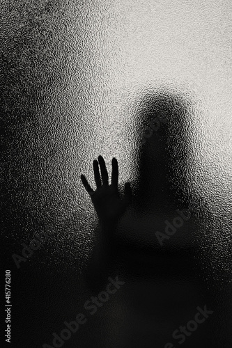 silhouette of a woman through frosted translucent glass, black and white image