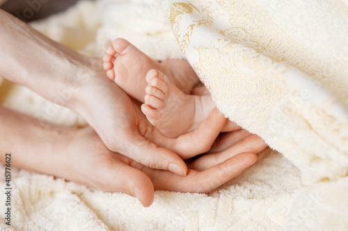 Newborn baby legs in mother’s nd father's palm. Happy parents holding theyr baby feet close up. Maternity, family, birth concept.