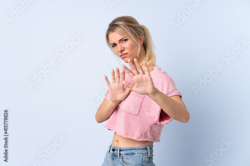 Blonde woman over isolated blue background nervous stretching hands to the front