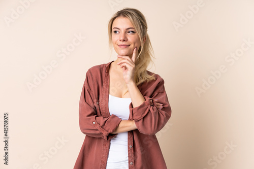 Blonde woman over isolated background thinking an idea while looking up