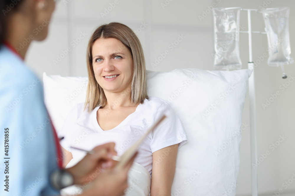 Doctor examining woman lying on bed in hospital Doctor examining woman lying on bed in hospital