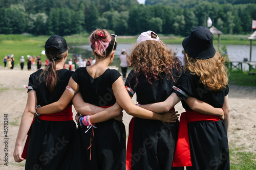 Four girls hug from behind in black cloth. A symbol of friendship