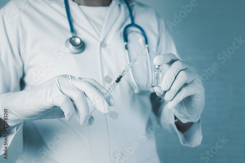 Doctor wear hand in white gloves holding a syringe with liquid vaccines for children or older adults,Concept fight against virus covid-19 corona virus