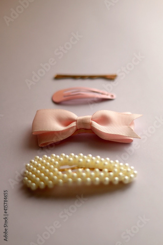 Pink, pearl and gold hair clips on pink background. Selective focus.