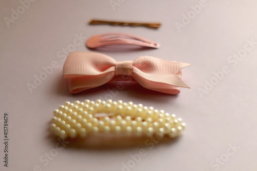 Pink, pearl and gold hair clips on pink background. Selective focus.