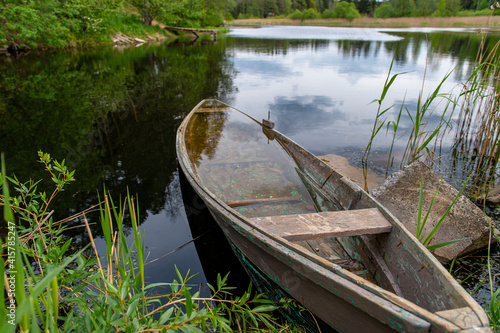 The overgrown pond with old wooden boat in calm water