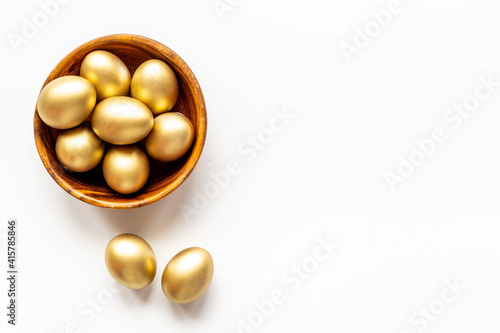 Golden Easter eggs in wooden bowl. Wealth and good luck concept.