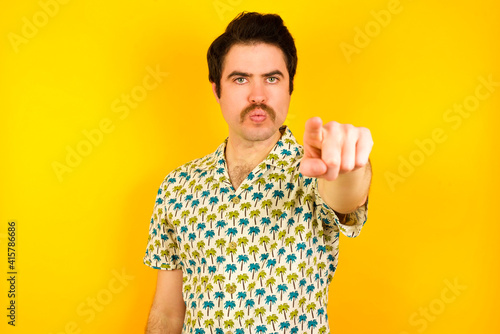 Bild auf Leinwand Cheerful young handsome Caucasian man wearing Hawaiian shirt against yellow wall indicates happily at you, chooses to compete, has positive expression, makes choice