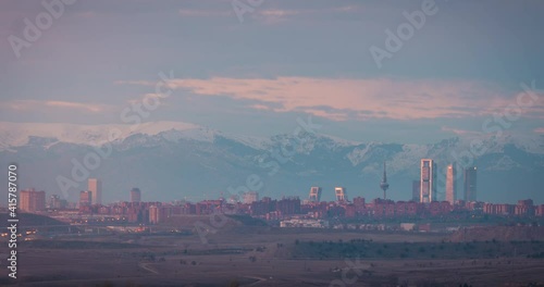 Madrid downtown skyline sunset time lapse day to night snowy Gadarrama mountains as background. photo