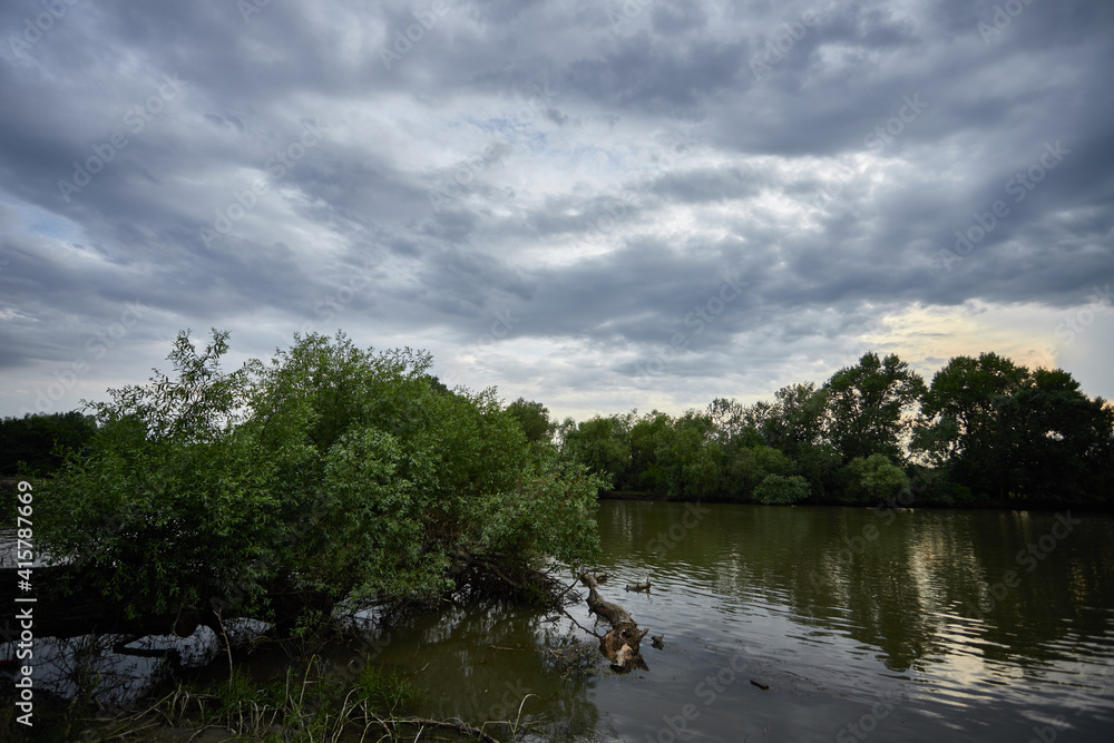 Summer, spring evening on the river, against the background of trees and sky with clouds Summer, spring evening on the river, against the background of trees and sky with clouds