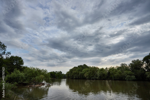 Summer, spring evening on the river, against the background of trees and sky with clouds