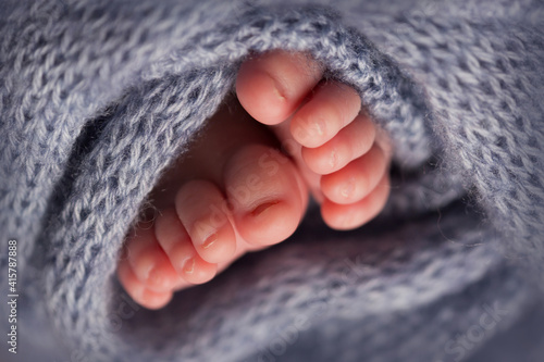 legs and toes of a newborn in a soft grey blanket