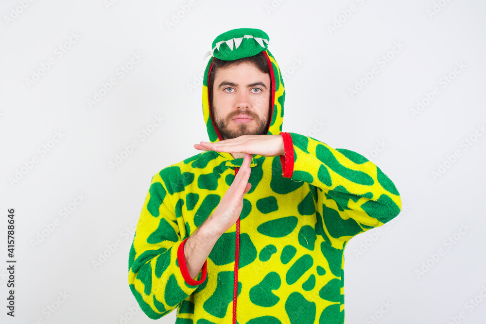 Fototapeta premium young caucasian man wearing a pyjama standing against white wall being upset showing a timeout gesture, needs stop, asks time for rest after hard work, demonstrates break hand sign