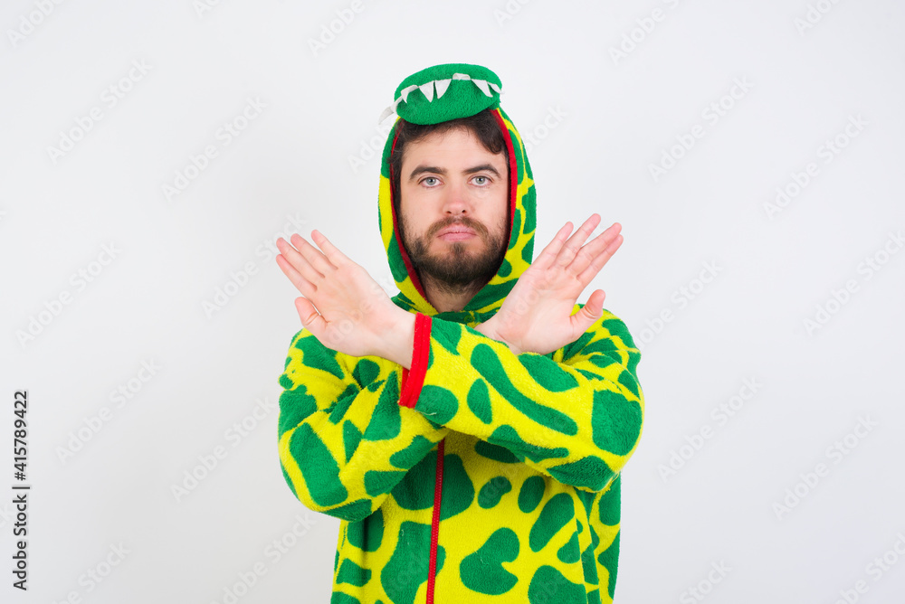 Fototapeta premium young caucasian man wearing a pajama standing against white wall has rejection expression crossing arms and palms doing negative sign, angry face.