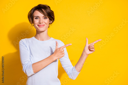 Photo of lady indicate forefingers empty space look camera wear white shirt isolated yellow color background photo