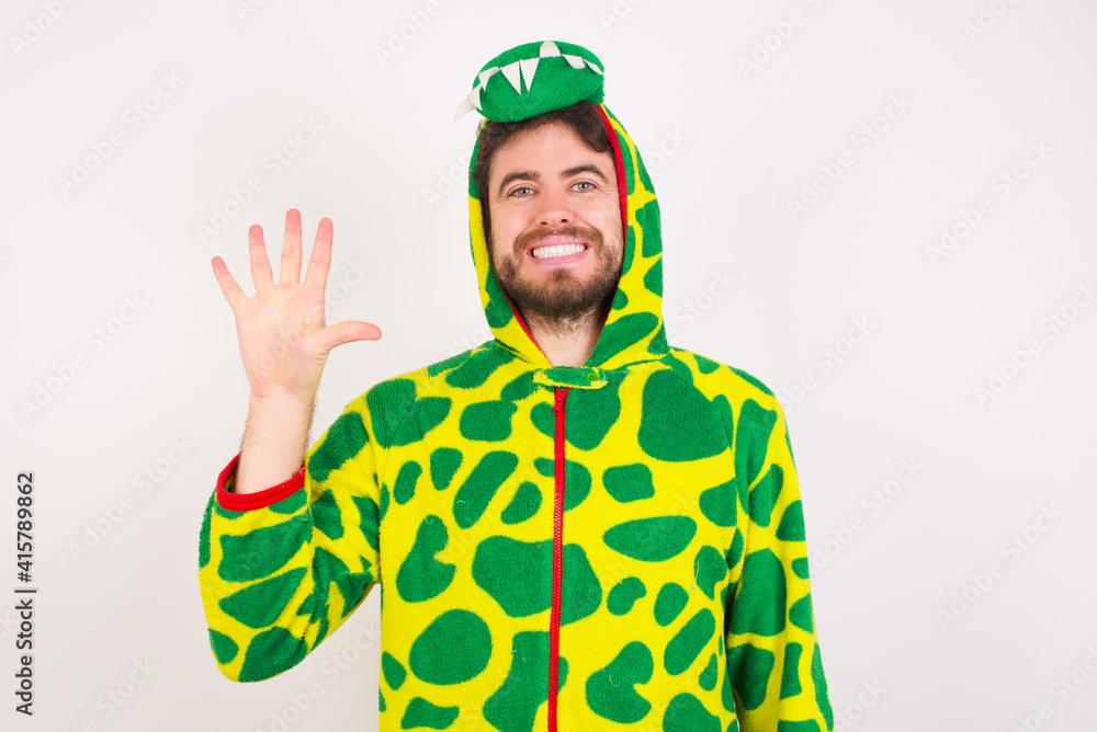 Fototapeta premium young caucasian man wearing a pajama standing against white wall showing and pointing up with fingers number five while smiling confident and happy.