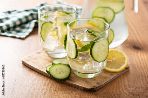 Sassy water or water with cucumber and lemon on wooden table