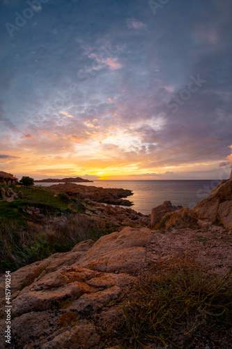 Picturesque view on colourful sky at sunset time. Jagged coastal rocks, Isola Rossa, Sardinia, Italy.