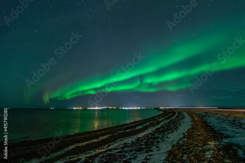 Green northern lights on night sky with start over winter landscape. Aurora Borealis photo taken in Iceland.