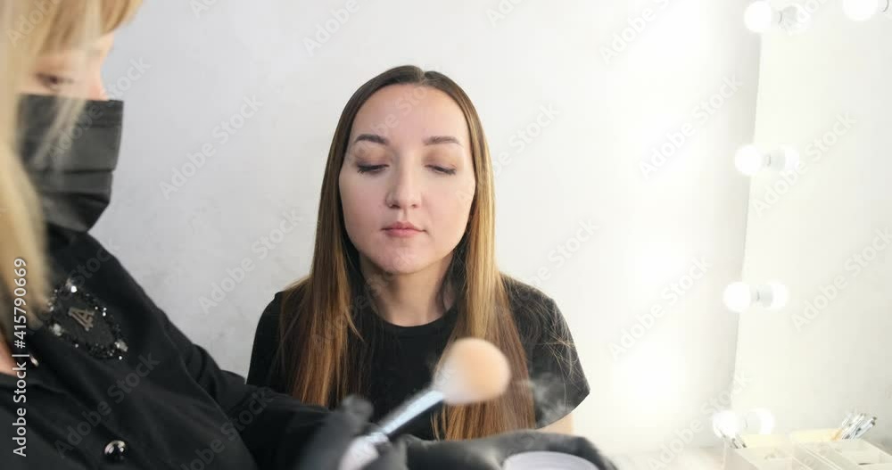 Woman make-up artist powders a beautiful girl Woman make-up artist powders a beautiful girl