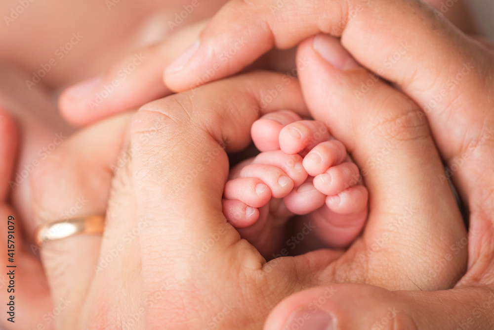Loving parent hold baby's legs. Happy childhood. Parental care. Concept of a happy family. Loving parent hold baby's legs. Happy childhood. Parental care. Concept of a happy family.