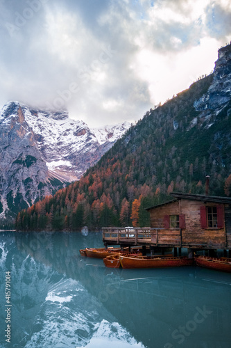 Several rowing boats at wooden pier and rental building, Lake Braies, South Tyrol, Italy. Autumn mountain landscape photo.