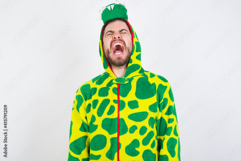 Fototapeta premium young caucasian man wearing a pajama standing against white background angry and mad screaming frustrated and furious, shouting with anger. Rage and aggressive concept.