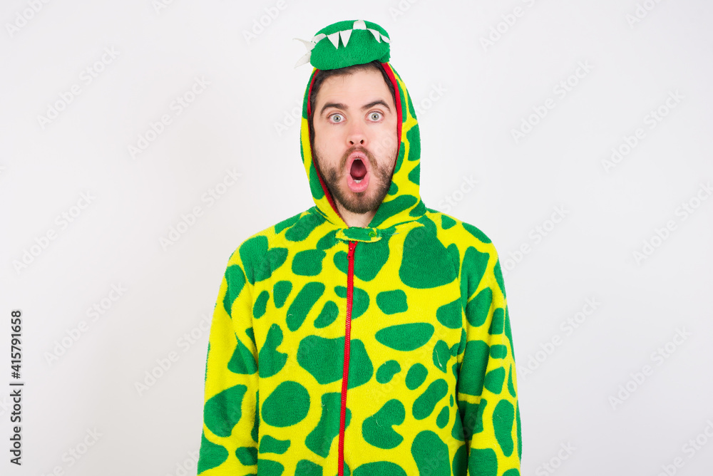 Fototapeta premium Oh my God. Surprised young caucasian man wearing a pajama standing against white background stares at camera with shocked expression exclaims with unexpectedness,