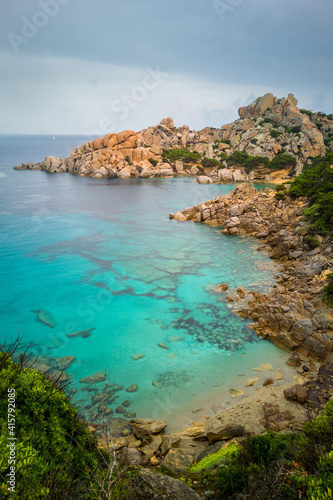 Clear sea water in bay at Capo Testa, Sardinia, Italy. Vivid blue/cyan water in shallow cove and eroded rock formation.