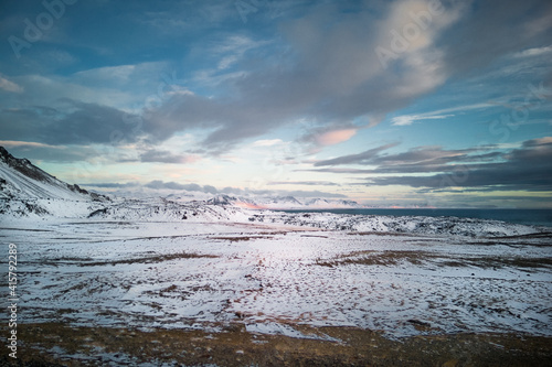 Snow-covered arctic landscape. Winter in Iceland nature - vast plains snow-capped distant mountains and rippled water surface.