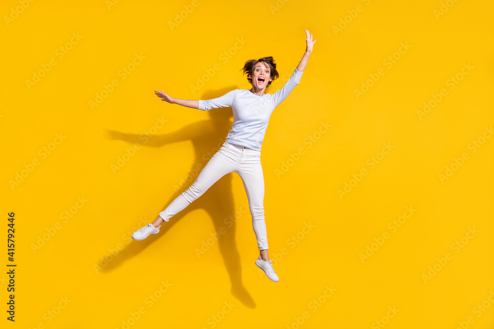 Full length photo of sweet pretty young lady dressed white shirt jumping waving arm isolated yellow color background