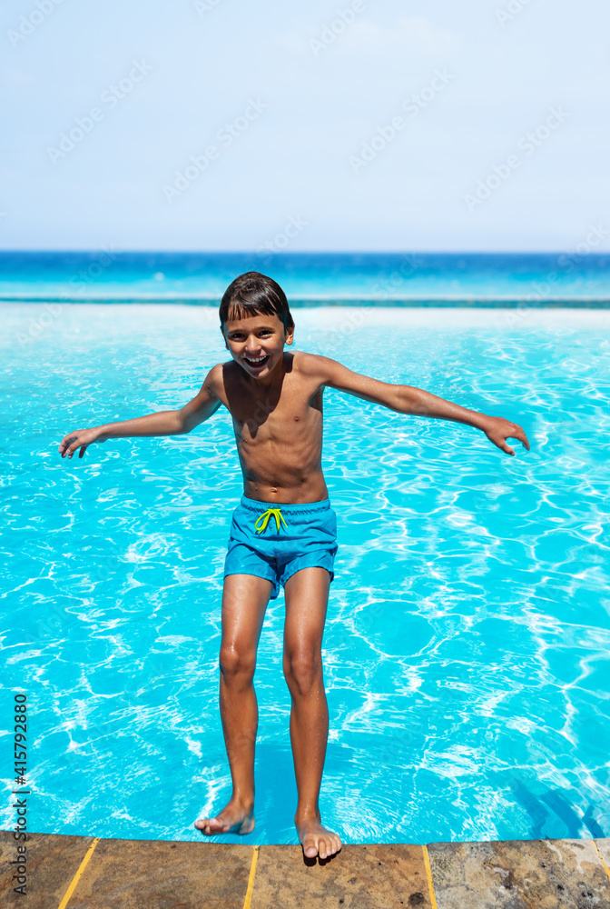 Happy little boy have fun falling backwards into swimming pool laughing