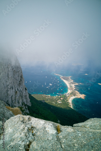 Aerial view of boats and yachts moored in bay from lookout at rock. Summer vacation concept. View from bottom level of clouds.