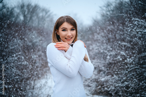 Cute blonde in a knitted sweater in the winter forest. Portrait
