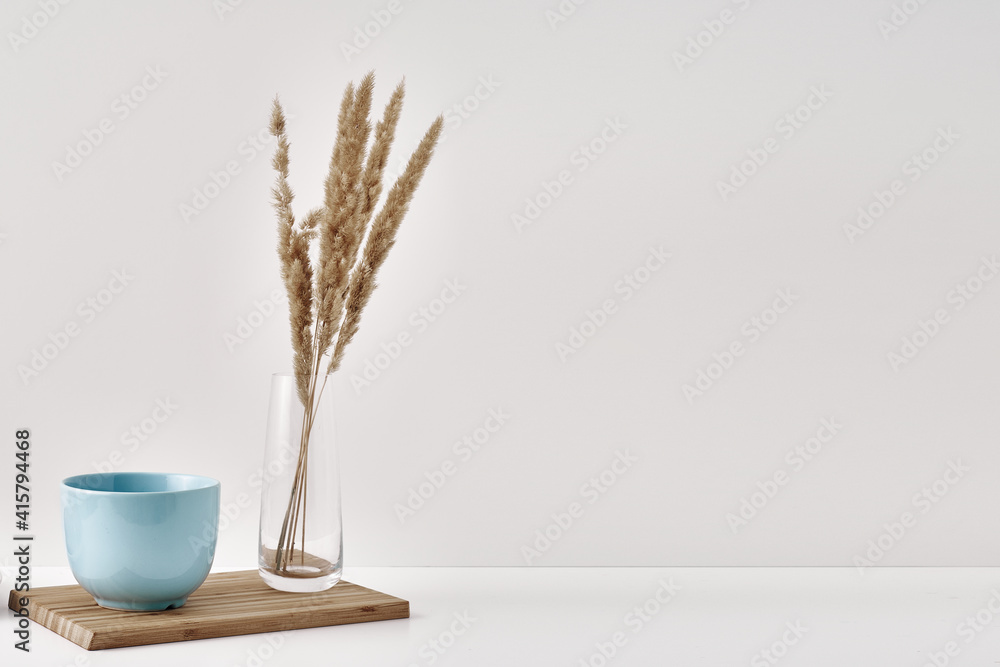 Naklejka premium A transparent vase with dry branches and mug on a white background. Minimalism, eco-materials in the interior decor. Copy space, mock up.