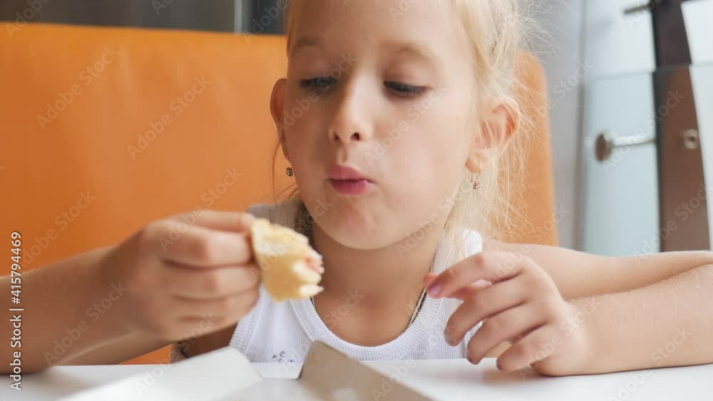 Beautiful young girl eating chicken in the cafe. The child greedily eating chicken, fat and delicious, very hungry. Beautiful young girl eating chicken in the cafe. The child greedily eating chicken, fat and delicious, very hungry.