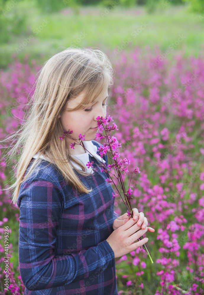 girl in a cellular dress in the field and sniffs a bouquet of flowers girl in a cellular dress in the field and sniffs a bouquet of flowers