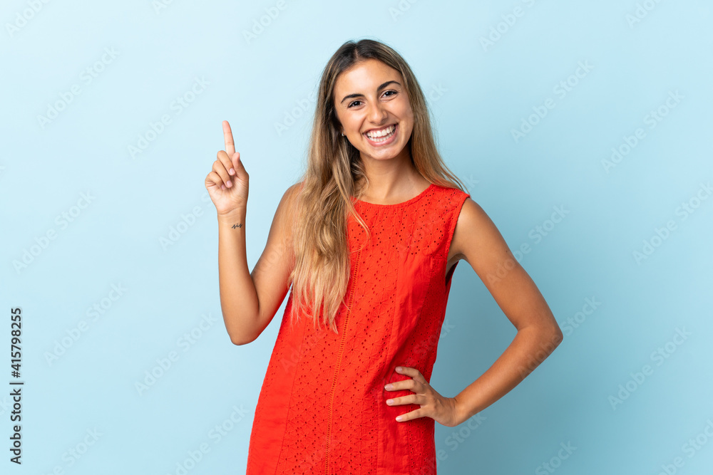 Young hispanic woman over isolated blue background showing and lifting a finger in sign of the best Young hispanic woman over isolated blue background showing and lifting a finger in sign of the best