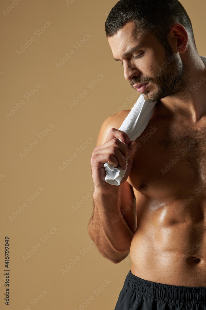 Fototapeta premium Bearded Caucasian athlete with muscular body posing at the camera in the indoors