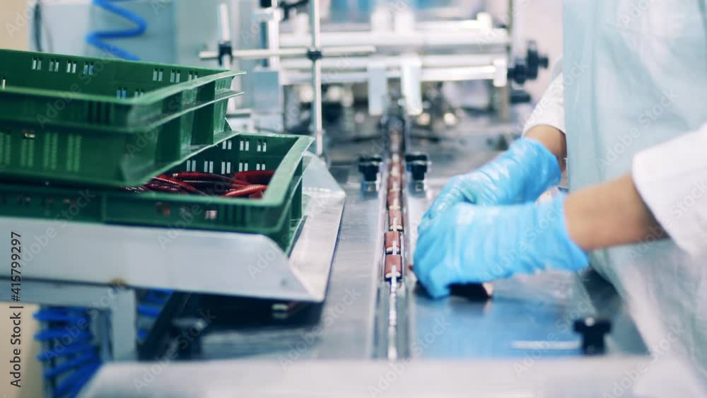 Factory worker is sorting candy bars and putting them into conveyor Factory worker is sorting candy bars and putting them into conveyor