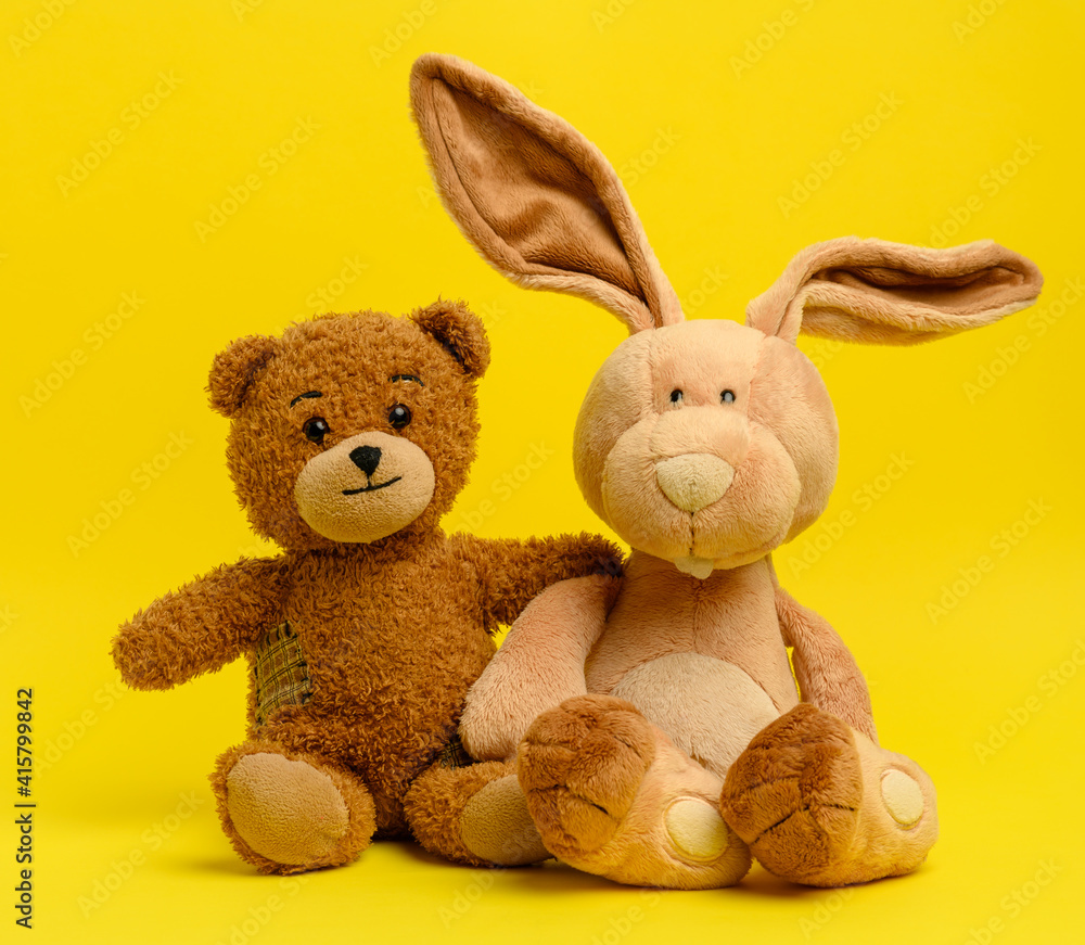 brown teddy bear and cute rabbit sit on a yellow background brown teddy bear and cute rabbit sit on a yellow background