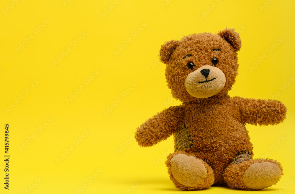 brown teddy bear sits on a yellow background brown teddy bear sits on a yellow background