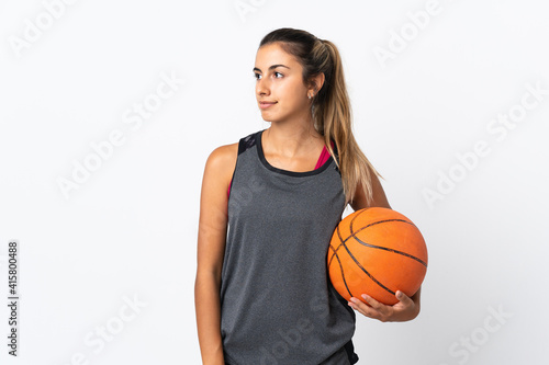Young hispanic woman playing basketball over isolated white background looking to the side © luismolinero
