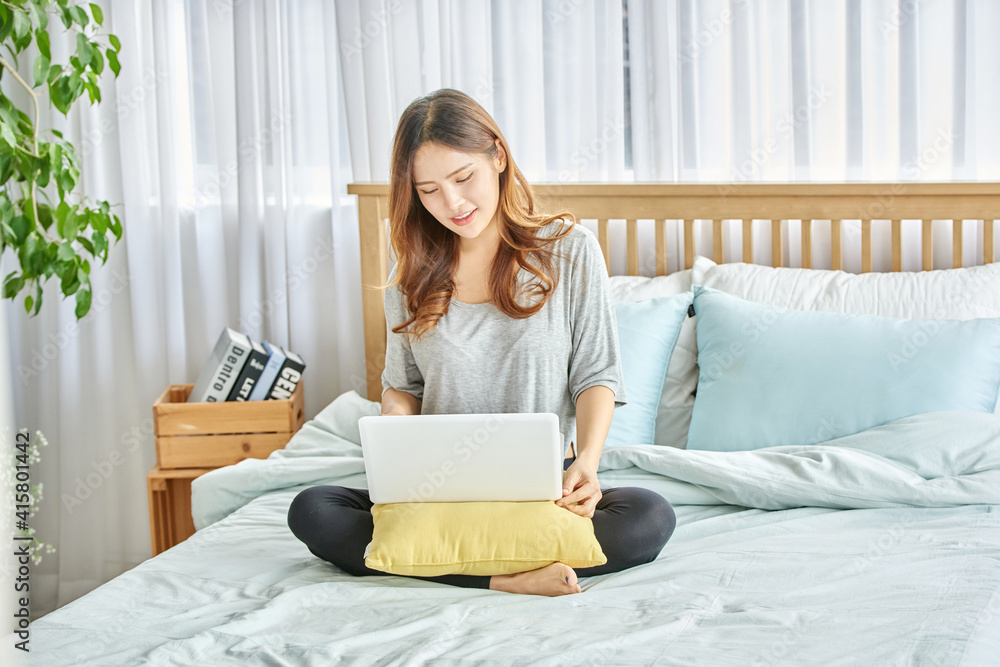 동양인 한국인 여성 모델 침대 위에서 노트북을 보며 스트레칭 